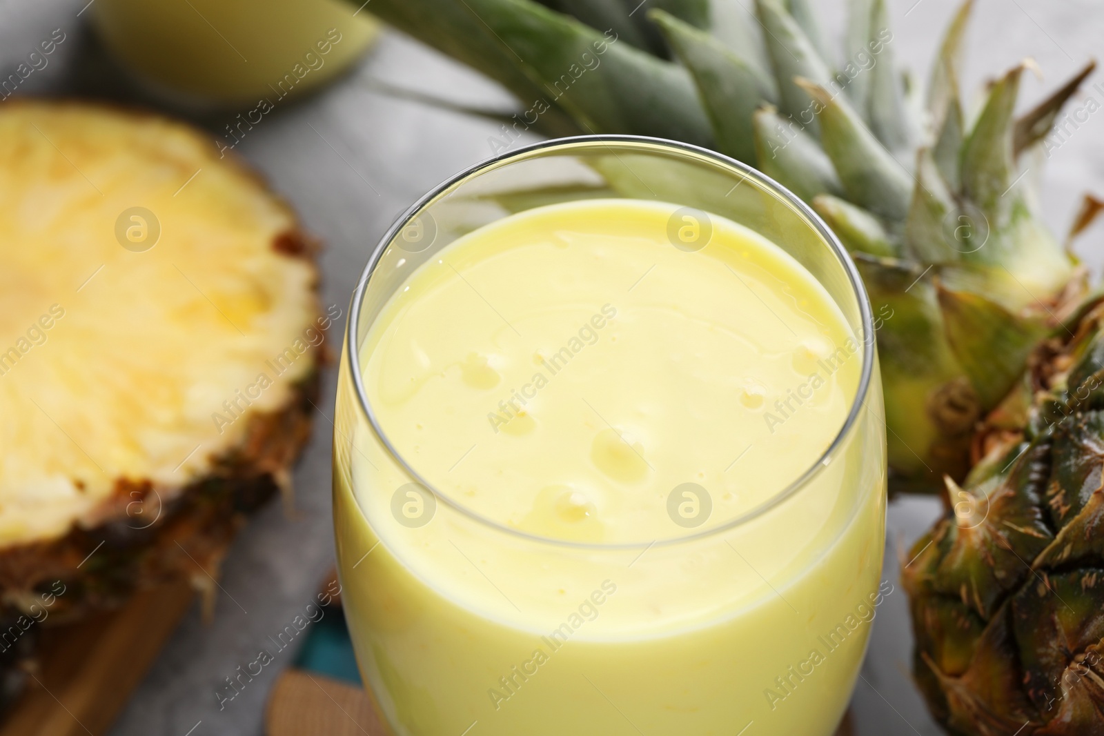 Photo of Tasty pineapple smoothie and fruit on grey table, closeup