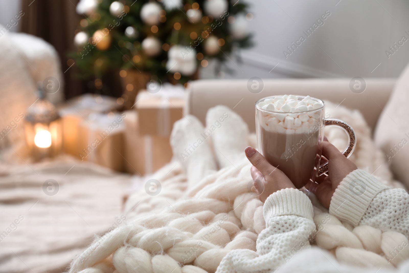 Photo of Woman with delicious hot drink wrapped in plaid on sofa at home, closeup. Space for text