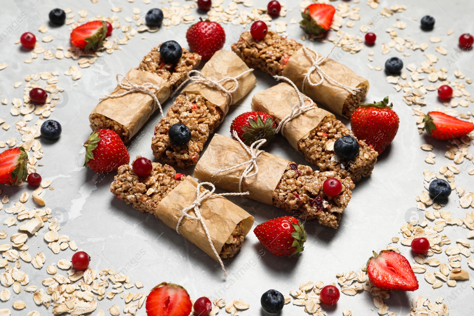 Photo of Tasty granola bars and ingredients on light grey marble table