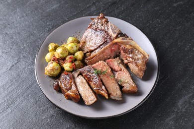 Photo of Delicious fried beef meat, vegetables and thyme on black table