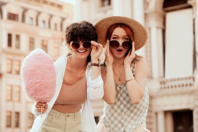 Happy friends with pink cotton candy outdoors on sunny day