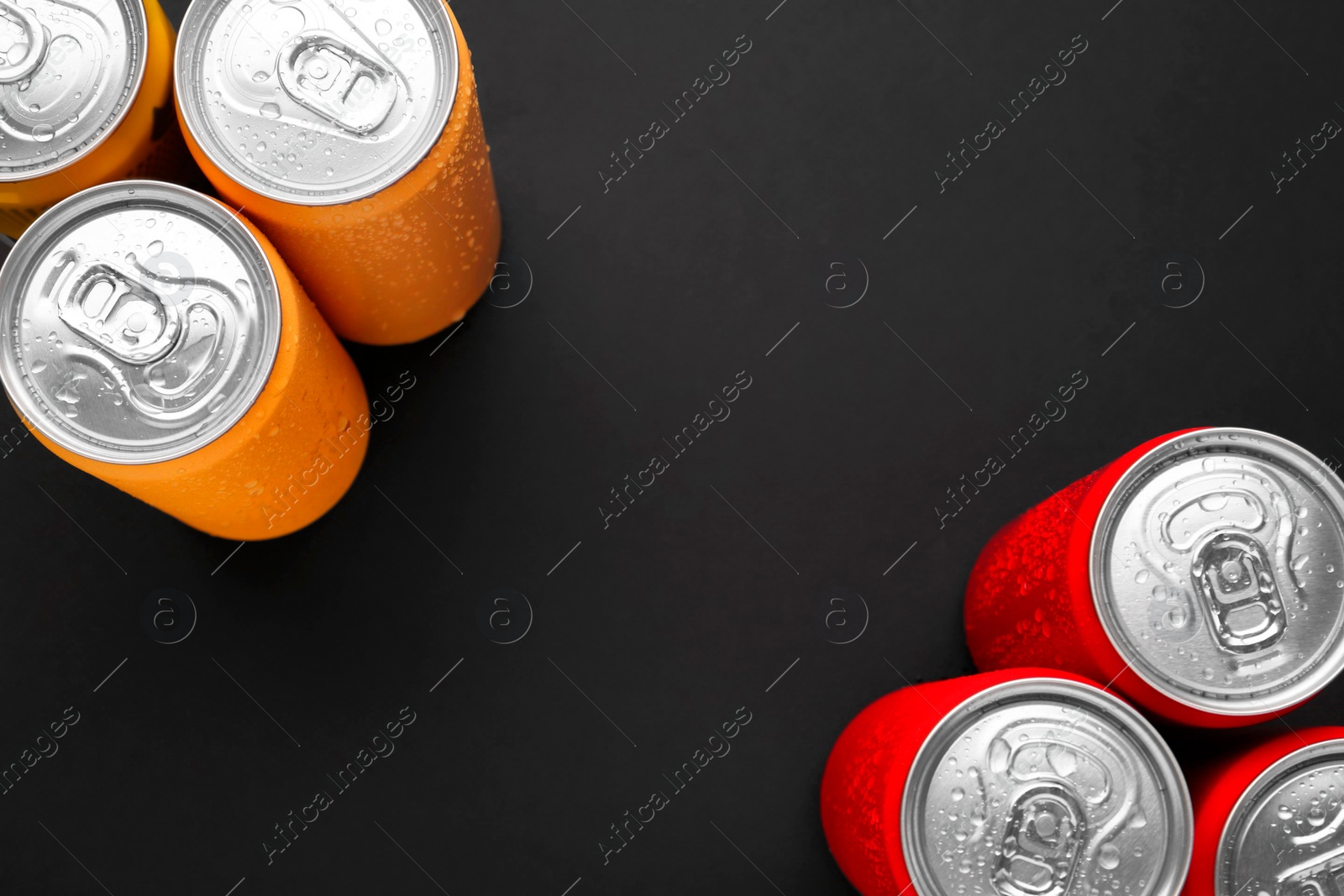 Photo of Energy drinks in wet cans on dark background, top view. Space for text