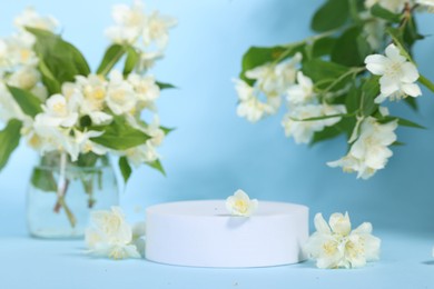 Presentation of product. White podium and beautiful jasmine flowers on light blue background, space for text