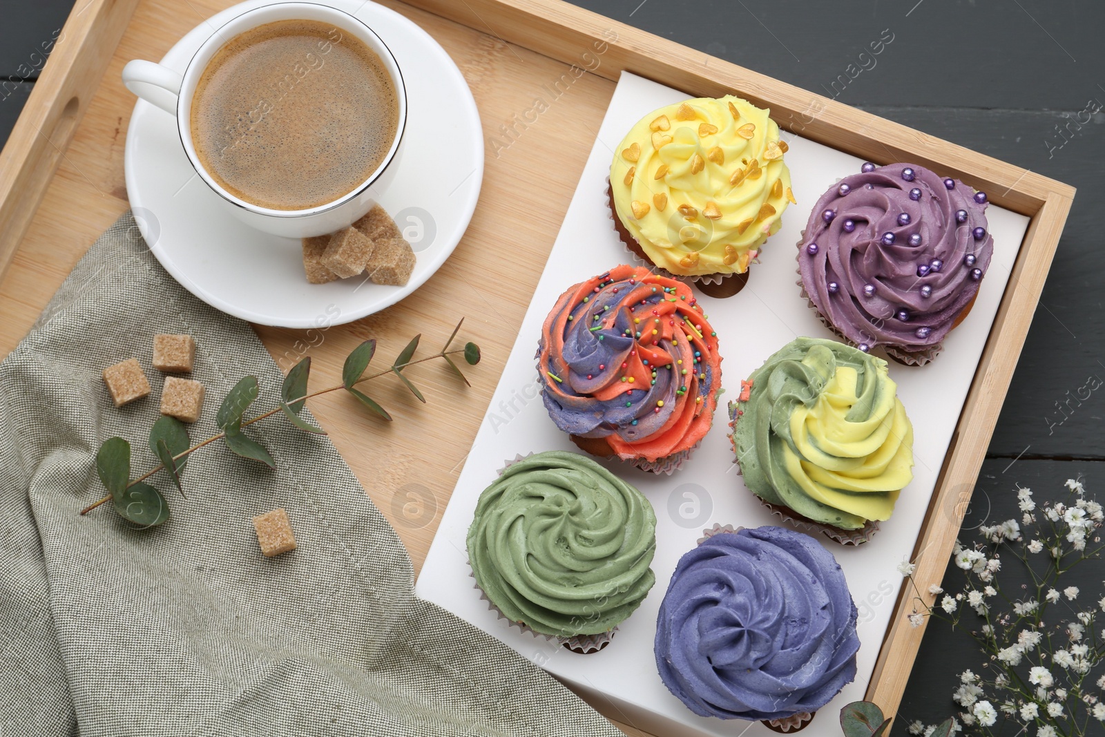 Photo of Different colorful cupcakes and coffee on grey table, top view