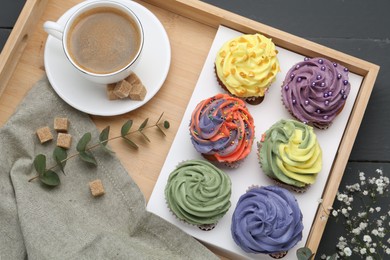 Photo of Different colorful cupcakes and coffee on grey table, top view