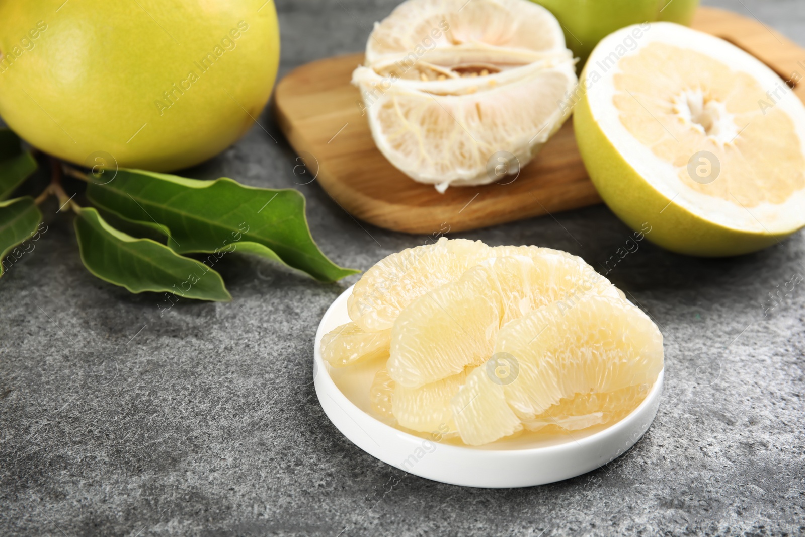 Photo of Peeled yellow pomelo slices on grey table