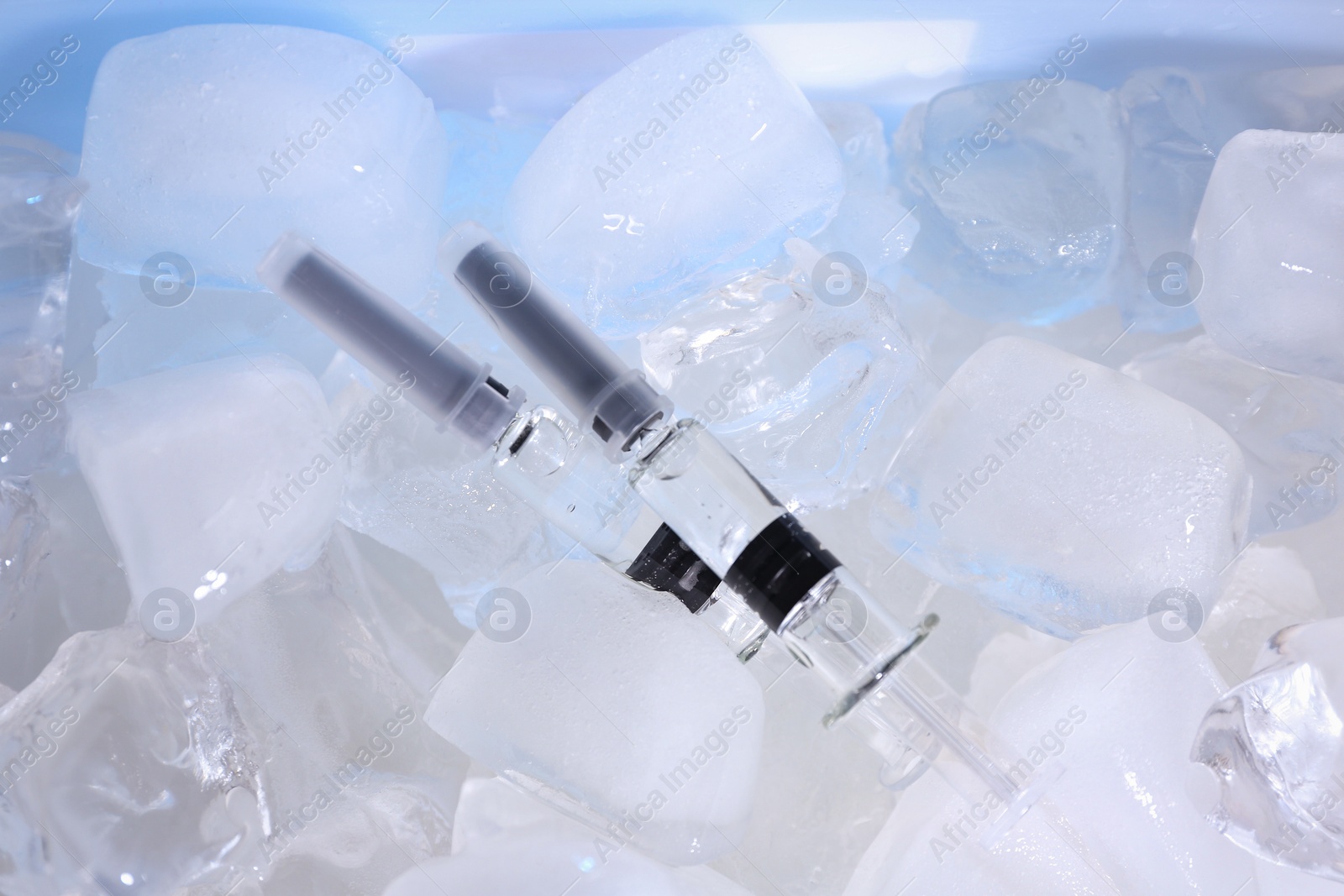 Photo of Syringes with COVID-19 vaccine on ice cubes