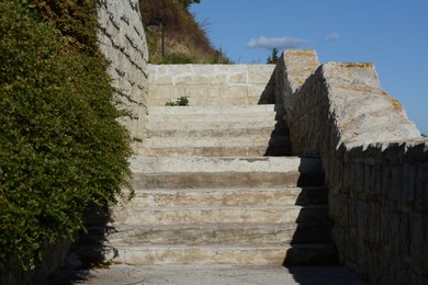 Old stone stairs near green plants outdoors on sunny day