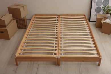 Photo of Wooden bed frame and cardboard boxes on floor in room