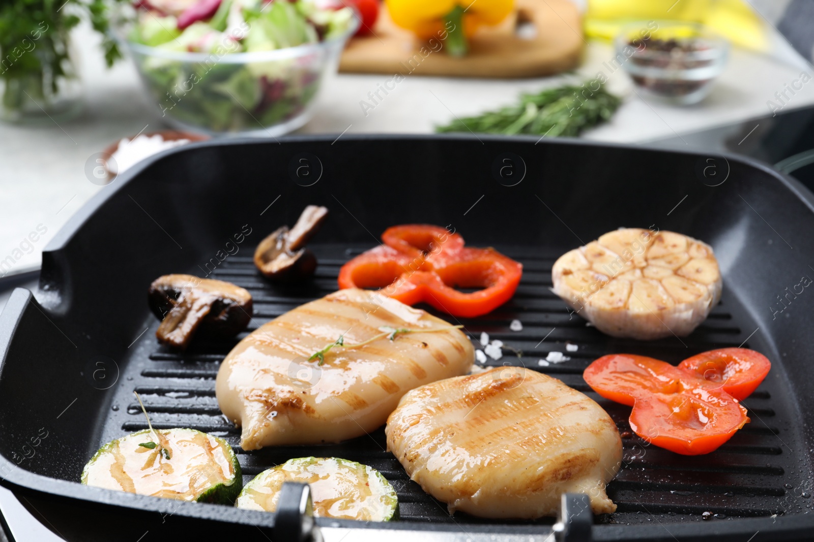 Photo of Cooking fresh squid tubes with vegetables and mushroom on grill pan, closeup