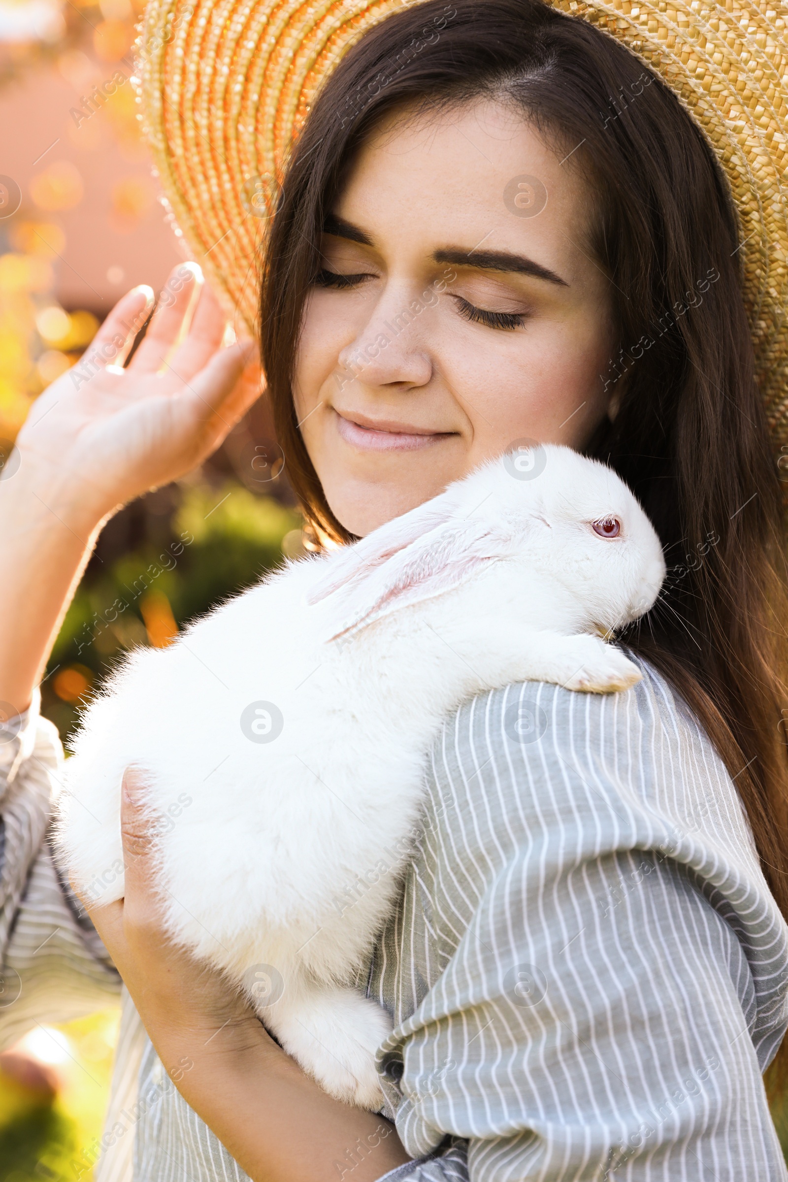 Photo of Happy woman with cute rabbit outdoors on sunny day