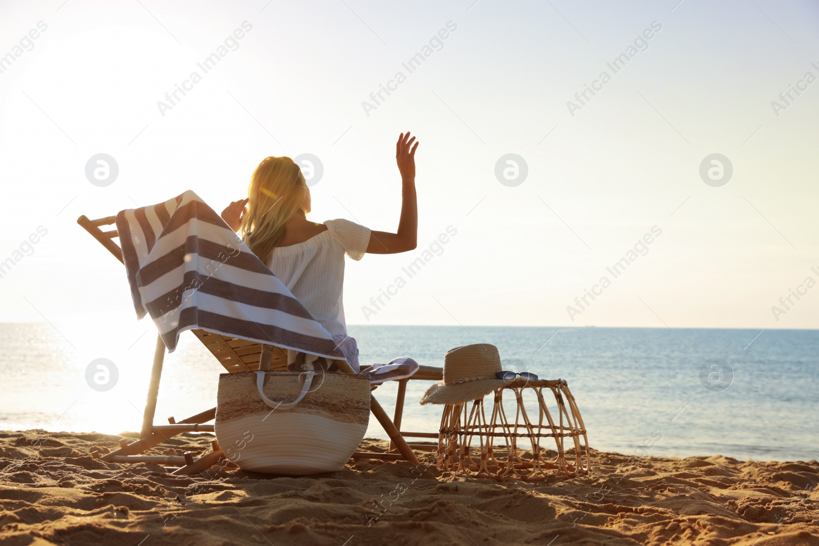 Photo of Woman relaxing on deck chair at sandy beach. Summer vacation