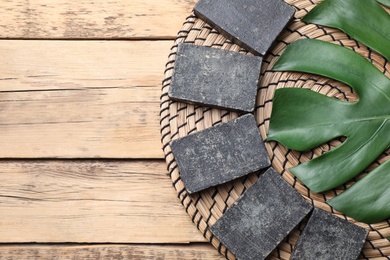 Photo of Natural tar soap and green leaf on wooden table, flat lay. Space for text