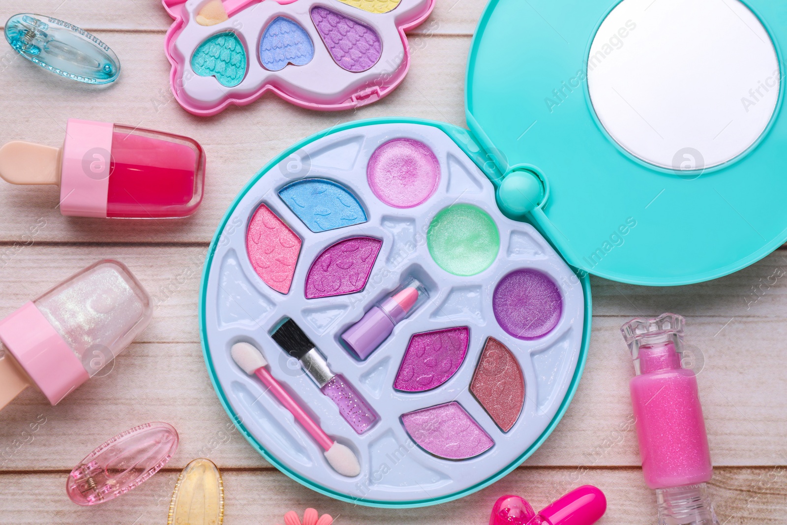 Photo of Decorative cosmetics for kids. Eye shadow palette, lipsticks and accessories on white wooden table, flat lay