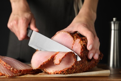 Photo of Woman cutting ham for dinner at table, closeup