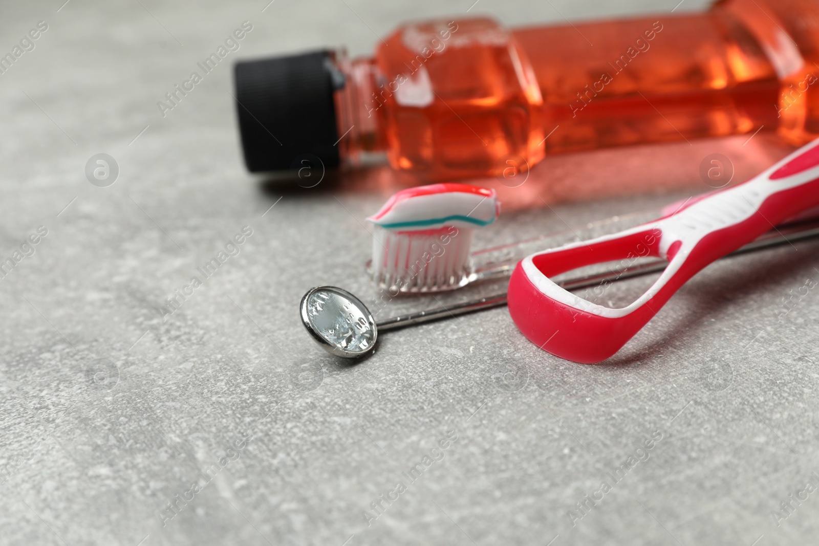 Photo of Composition with tongue cleaner and teeth care products on grey table, closeup. Space for text