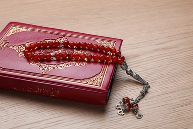 Photo of Muslim prayer beads and Quran on wooden table