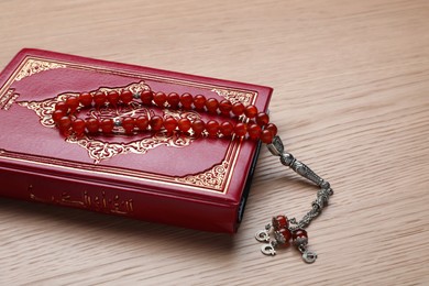 Muslim prayer beads and Quran on wooden table