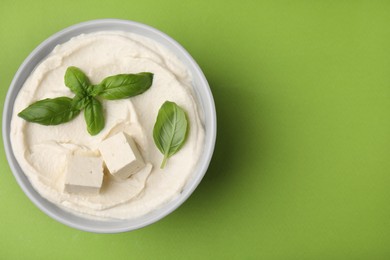 Photo of Delicious tofu sauce and basil leaves on green background, top view. Space for text
