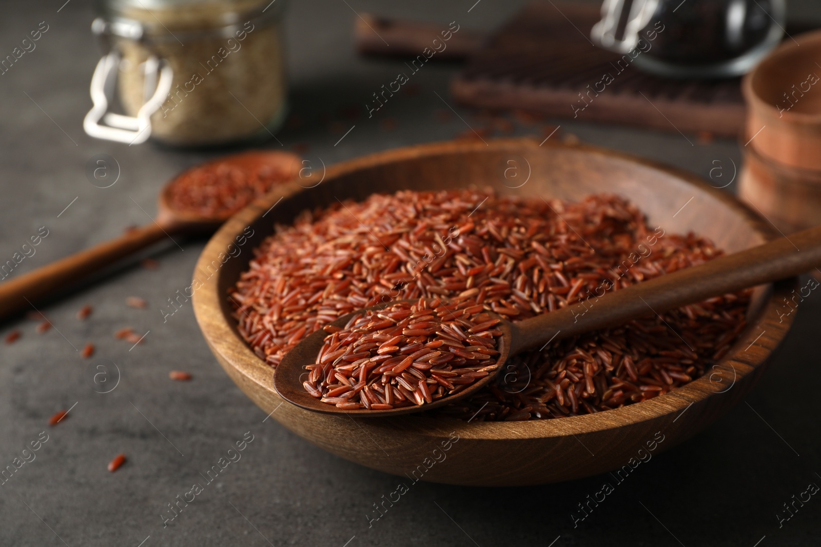 Photo of Brown rice in spoon and bowl on table