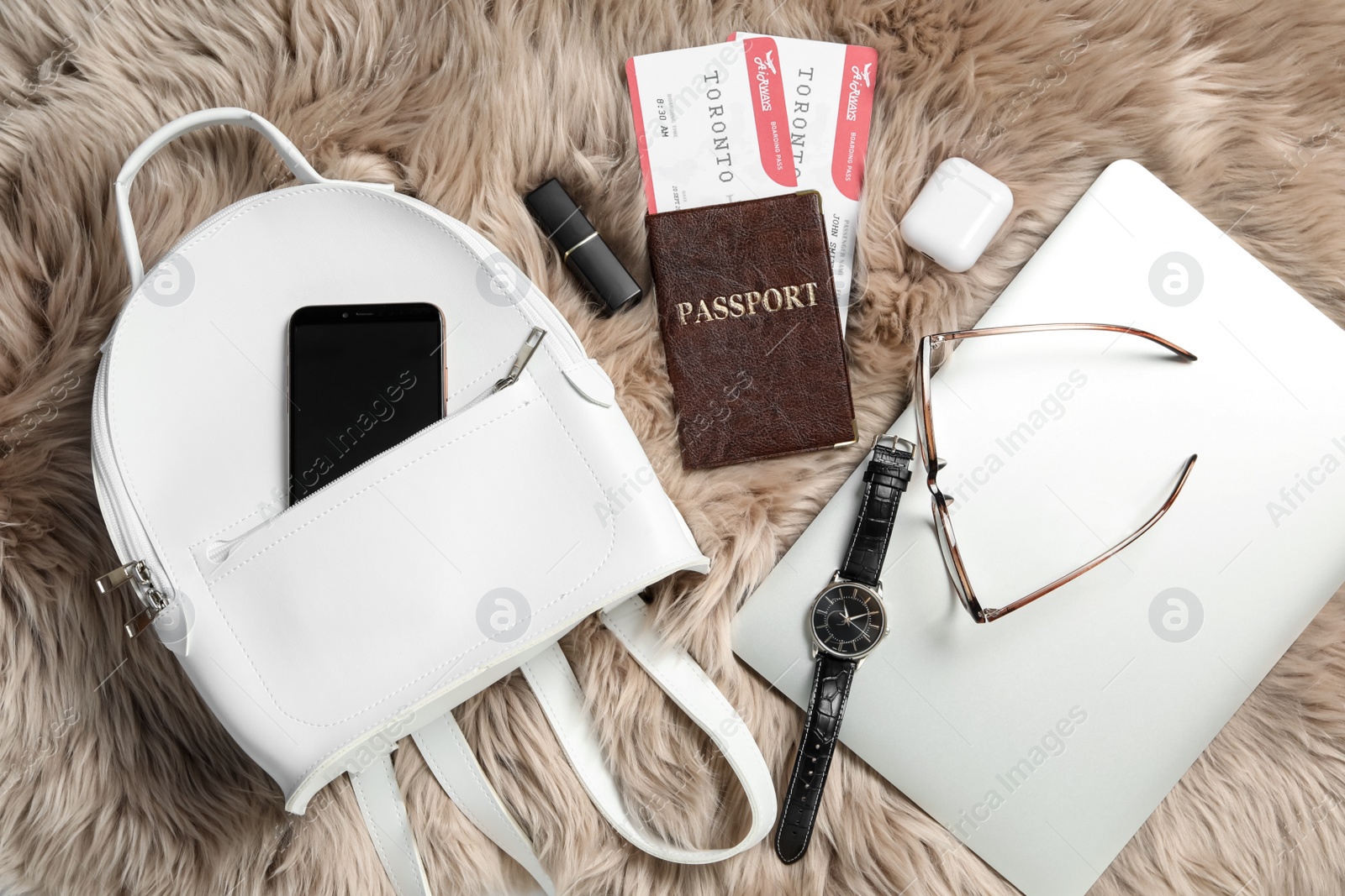 Photo of Stylish urban backpack and different items on brown faux fur, flat lay