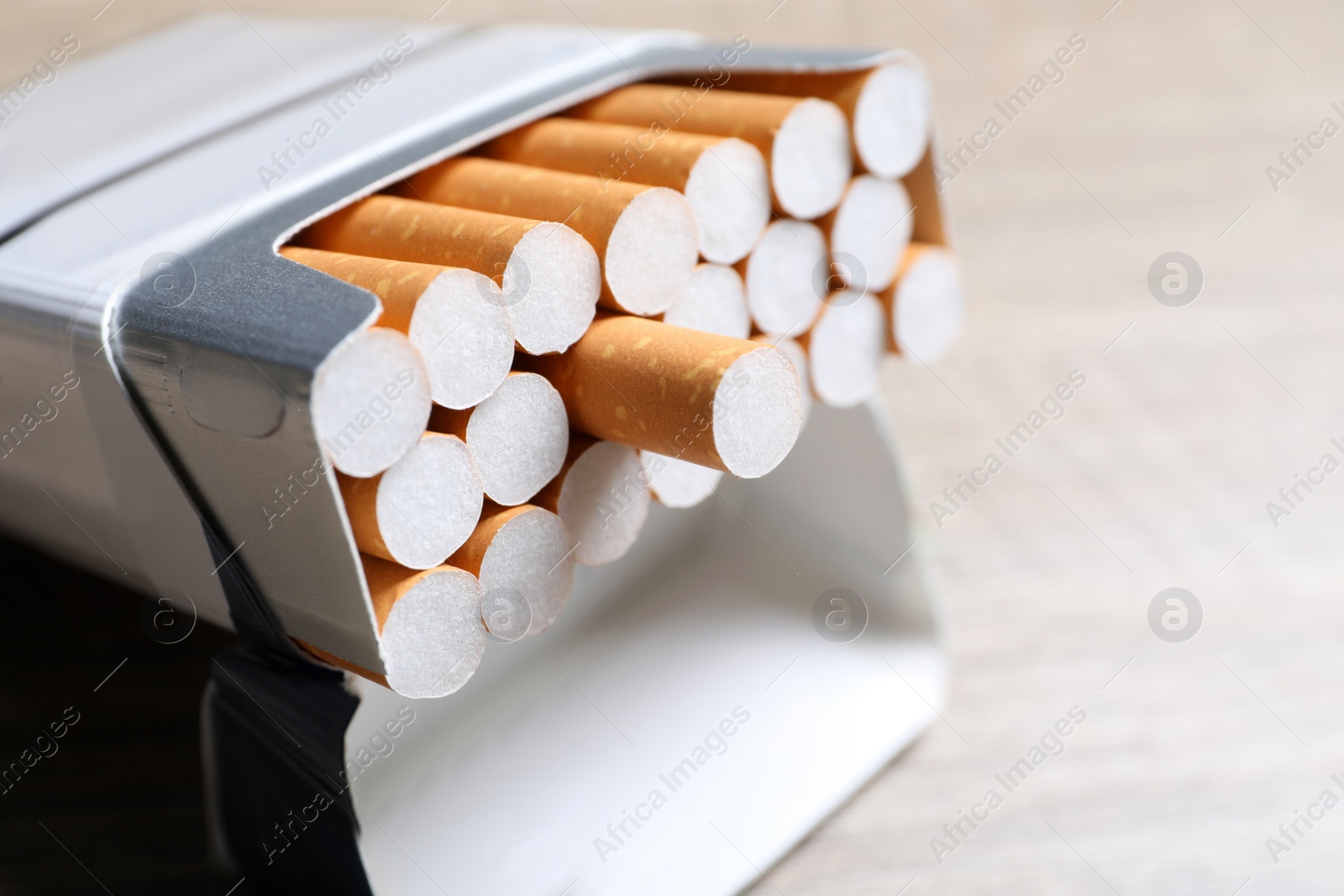 Photo of Cigarettes with orange filters in pack on table, closeup