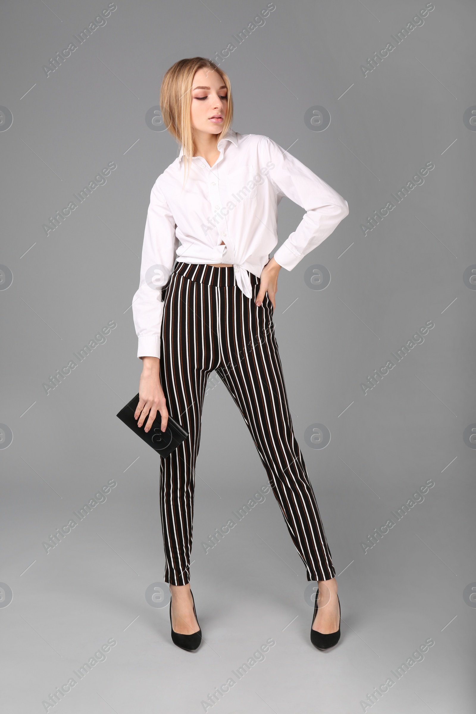 Photo of Young stylish woman in trendy shoes with bag on grey background