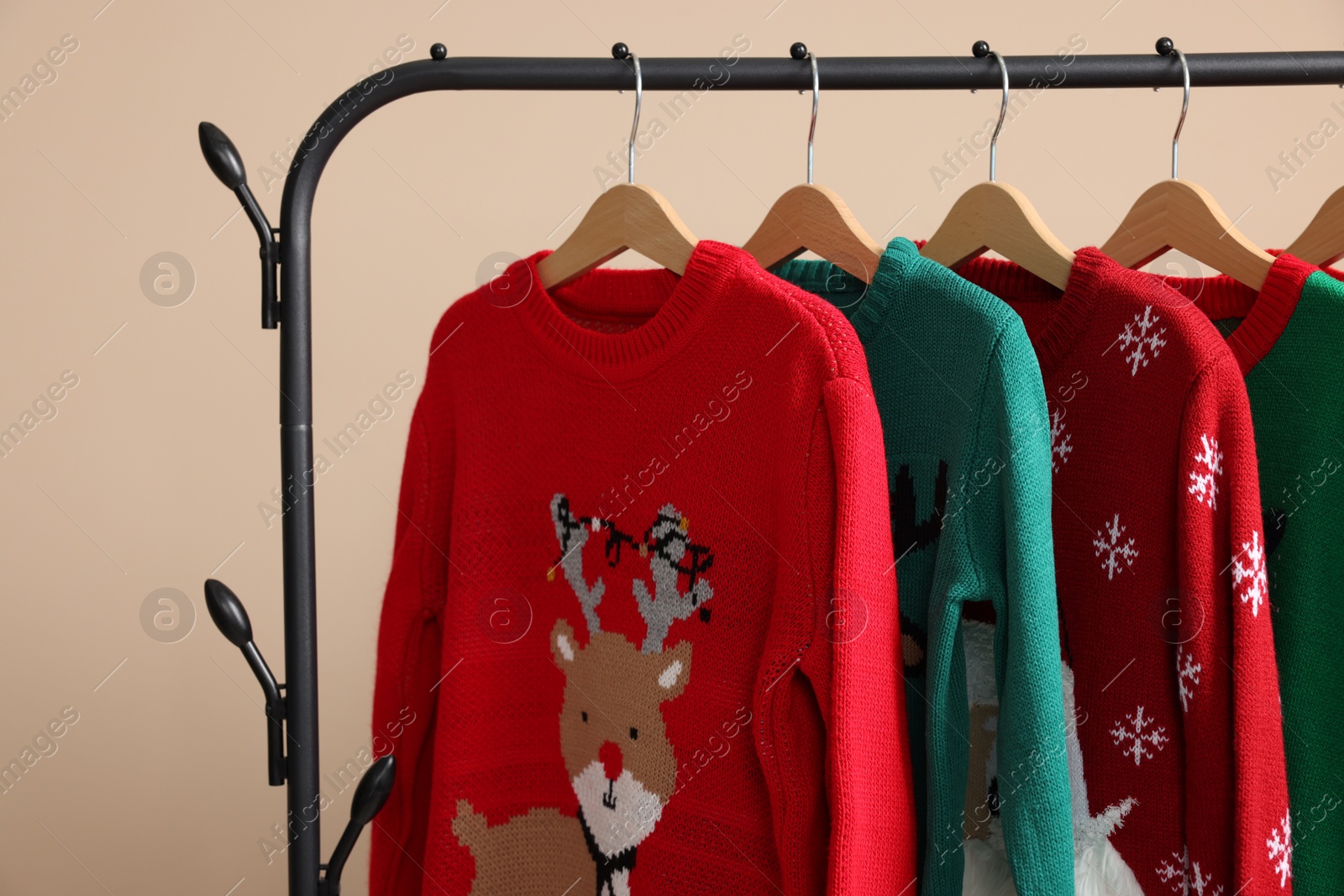 Photo of Rack with different Christmas sweaters on beige background