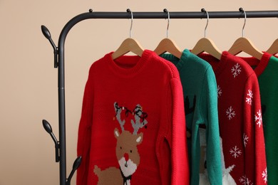 Photo of Rack with different Christmas sweaters on beige background