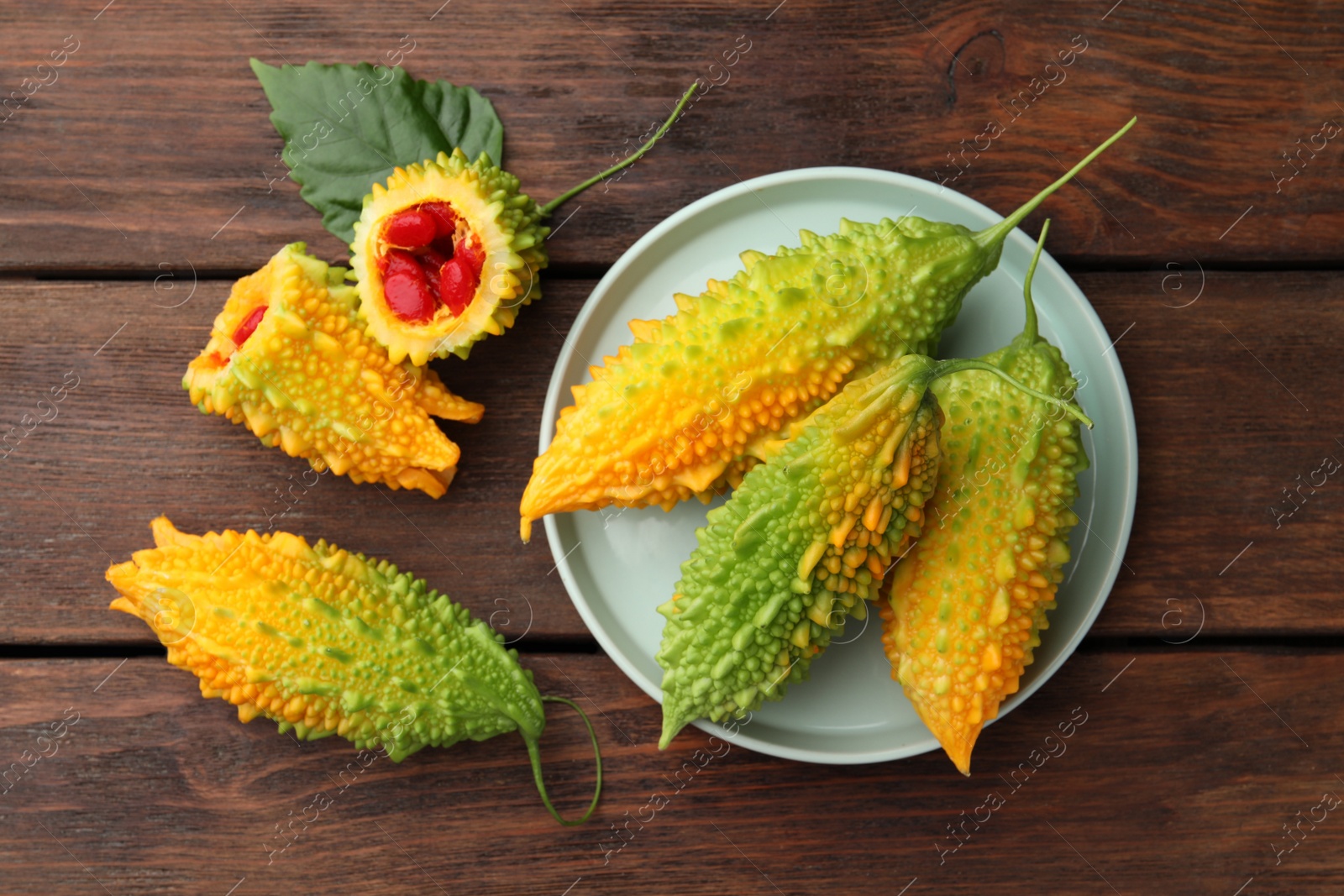 Photo of Fresh bitter melons on wooden table, flat lay