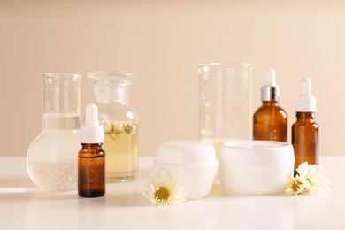 Skin care products, ingredients and laboratory glassware on table. Dermatology research