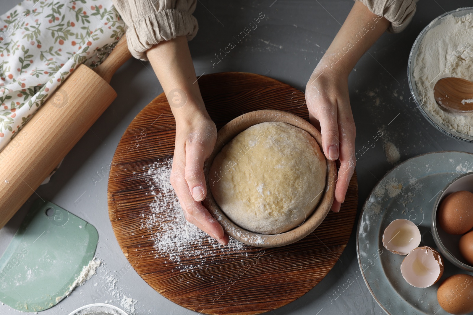 Photo of Woman making dough at grey table, top view