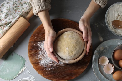 Photo of Woman making dough at grey table, top view