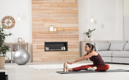 Photo of Young woman in fitness clothes doing exercise at home