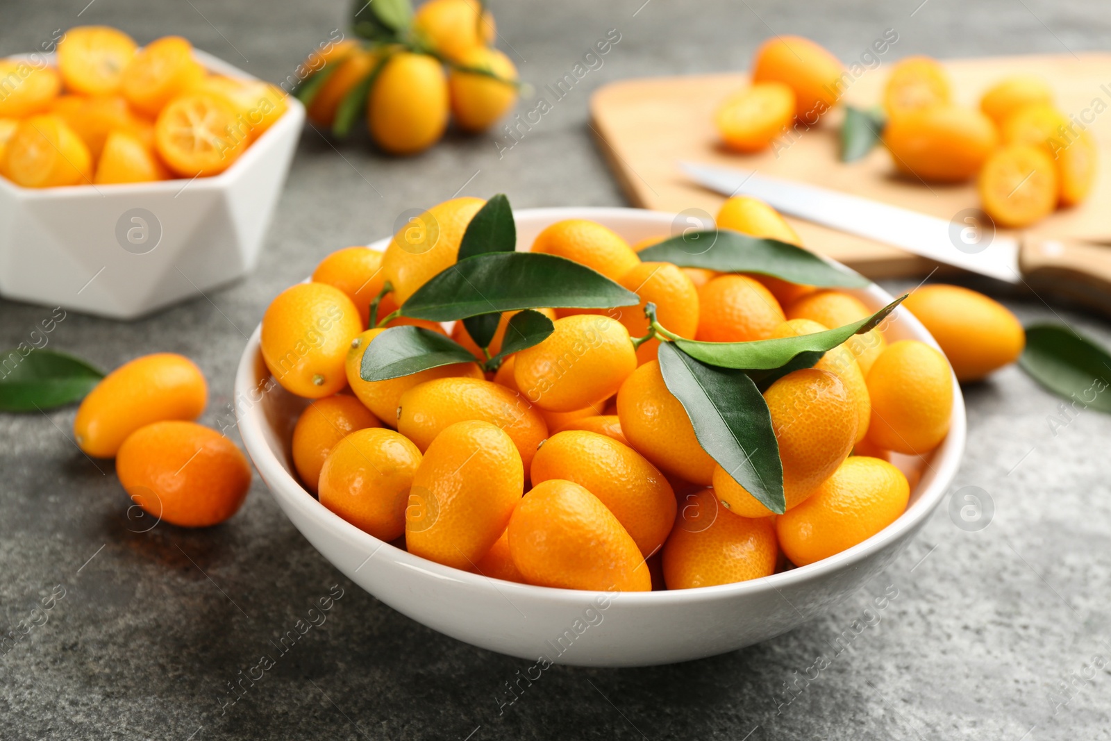 Photo of Fresh ripe kumquats in bowl on grey table