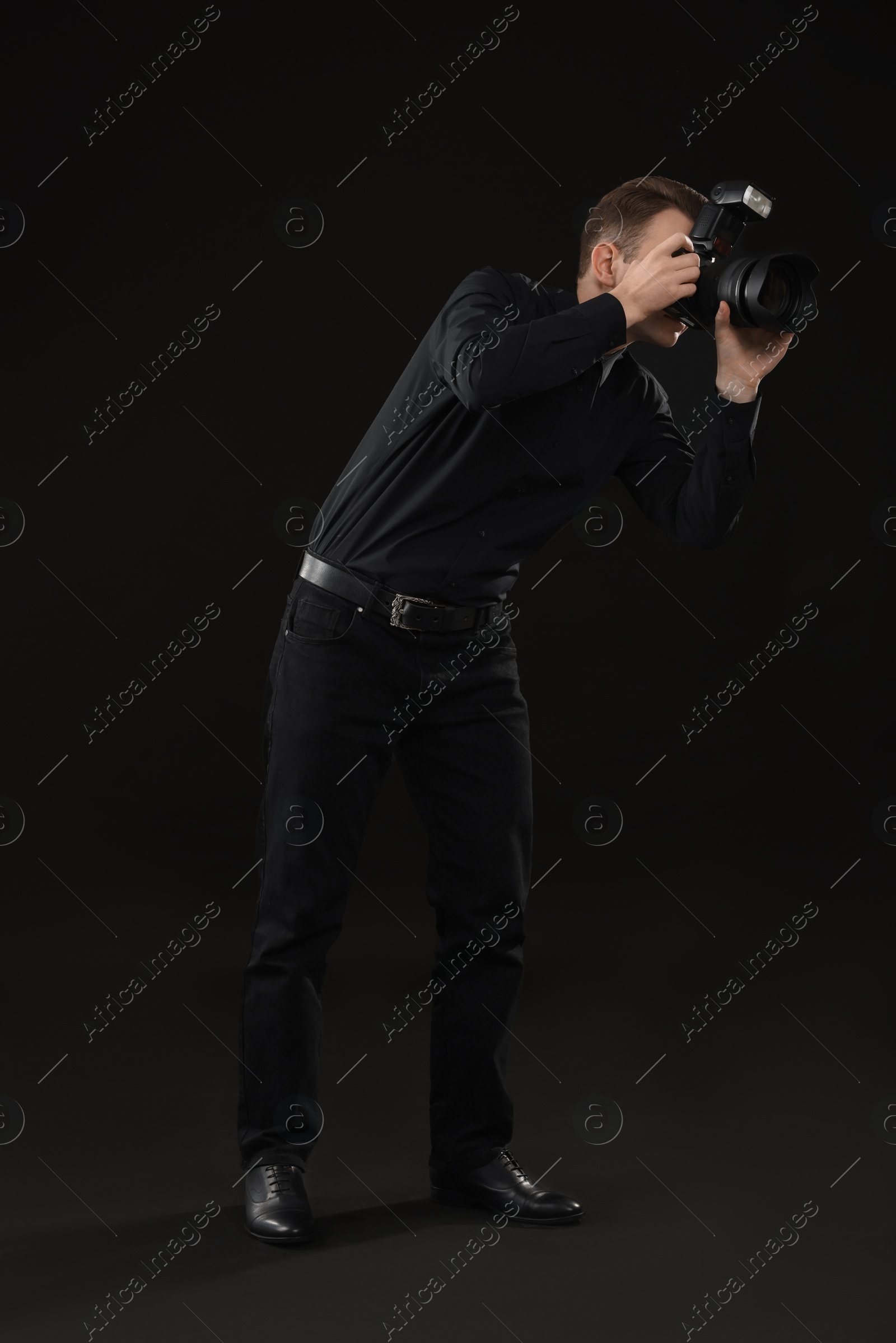 Photo of Professional photographer taking picture on black background