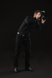 Professional photographer taking picture on black background