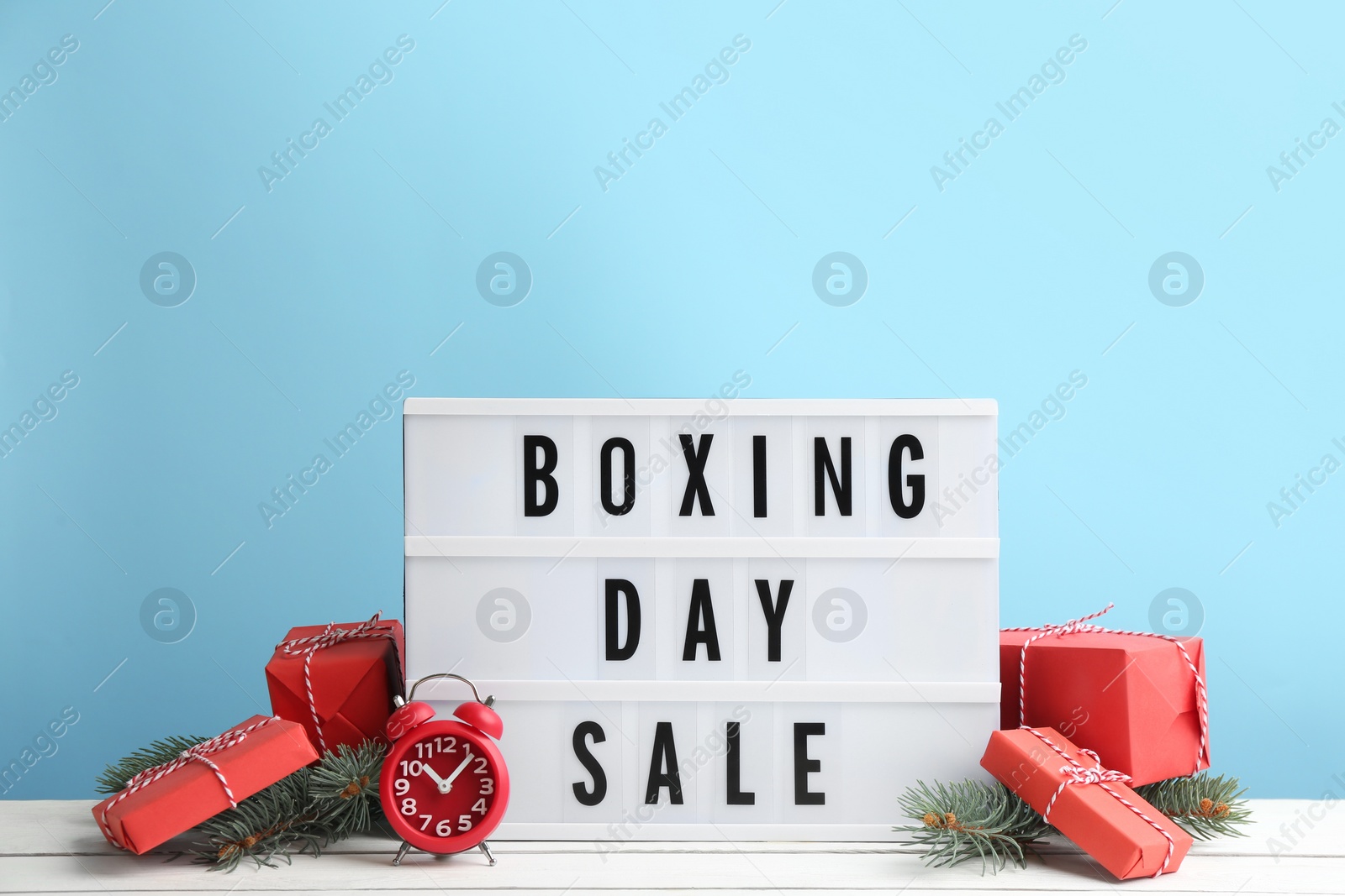 Photo of Composition with Boxing Day Sale sign and Christmas gifts on white table against light blue background