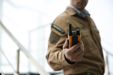 Photo of Professional security guard with portable radio set indoors, closeup