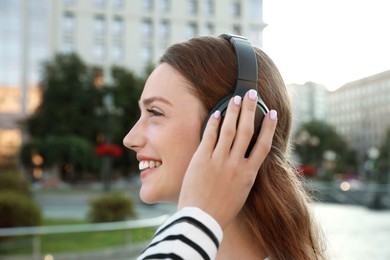 Happy woman in headphones listening to music on city street