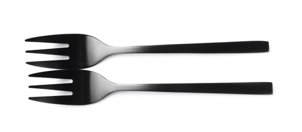 Photo of New black dessert forks on white background, top view