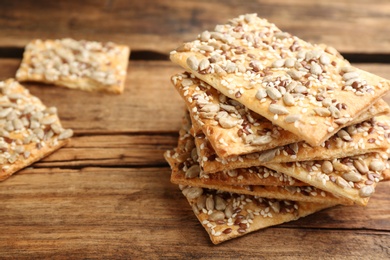 Photo of Stack of delicious crackers on wooden table, closeup