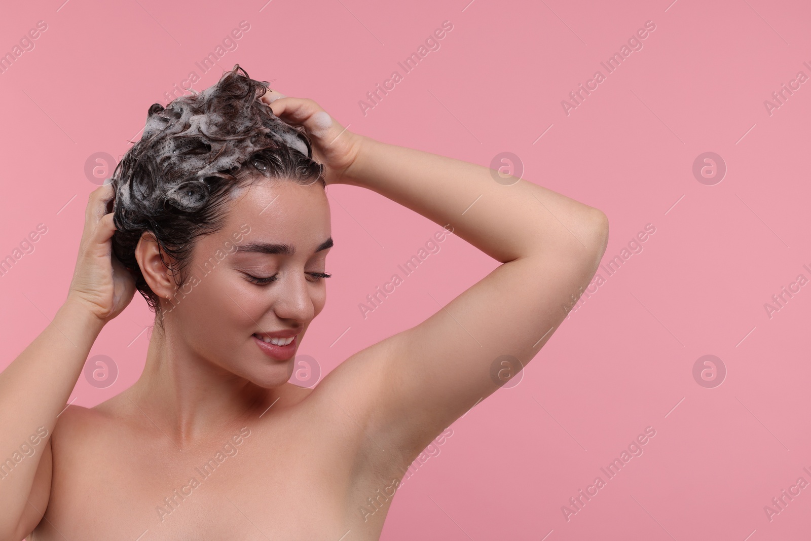 Photo of Beautiful happy woman washing hair on pink background. Space for text