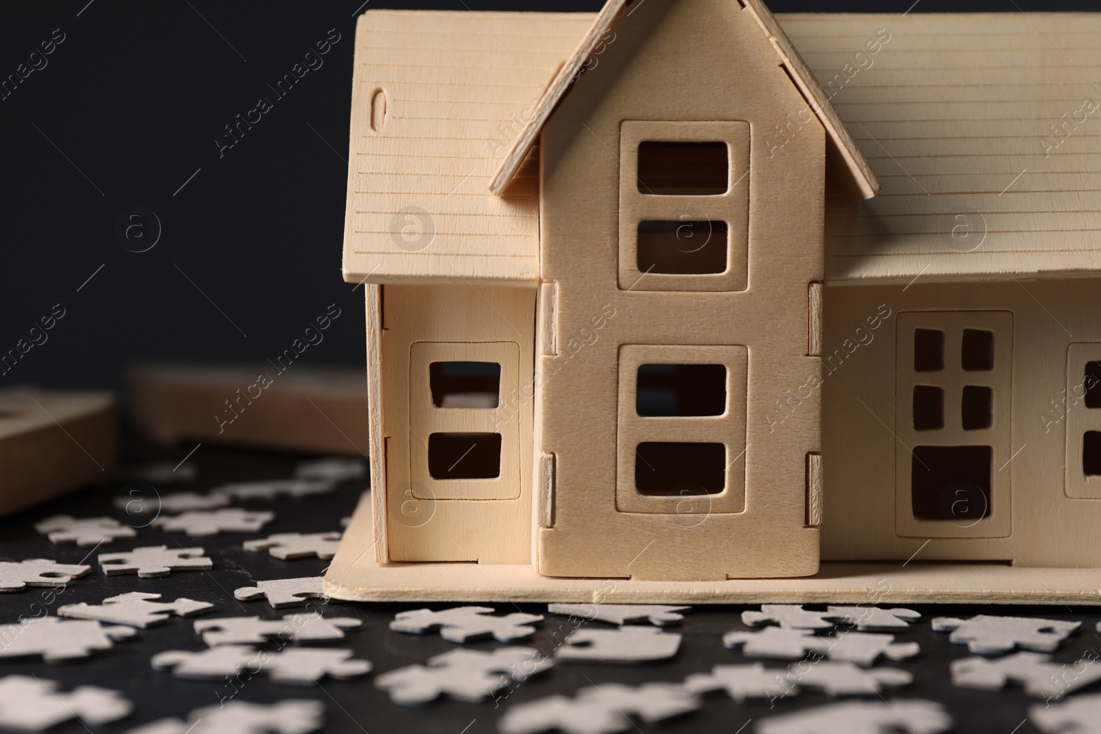 Photo of House model and puzzles on black table depicting destruction after earthquake