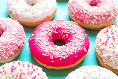 Photo of Delicious glazed doughnuts with sprinkles on color background