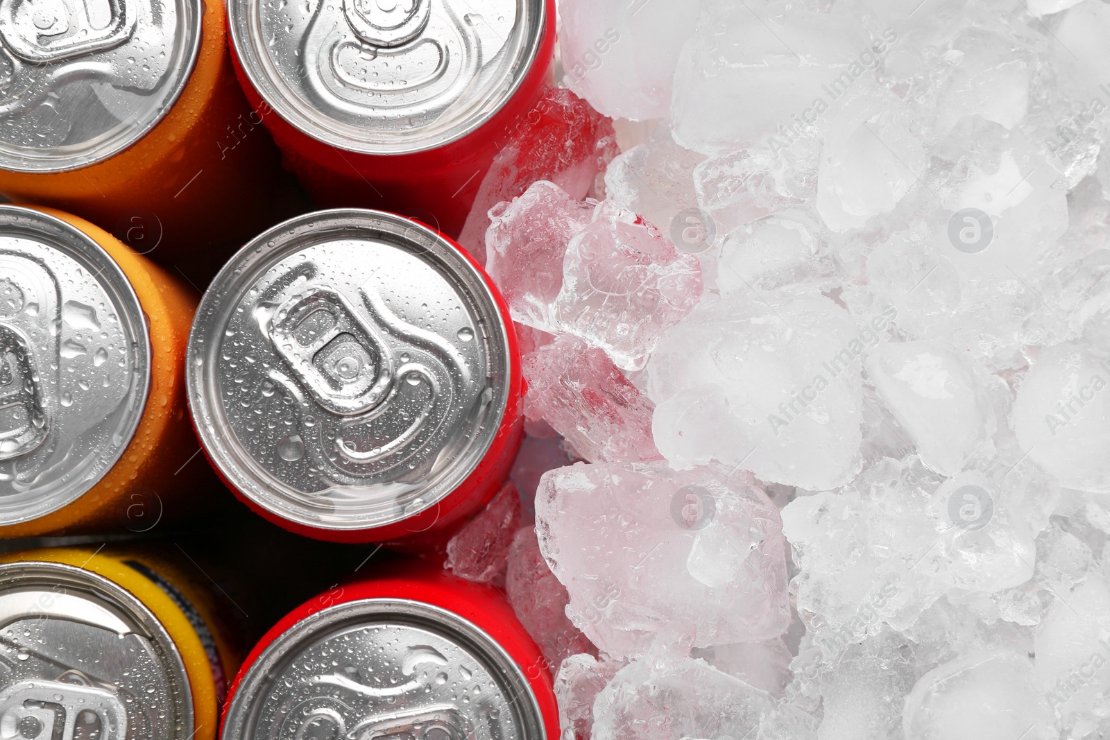 Photo of Energy drinks in wet cans and ice cubes, flat lay. Space for text