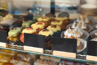 Photo of Different delicious desserts on counter in bakery shop, closeup