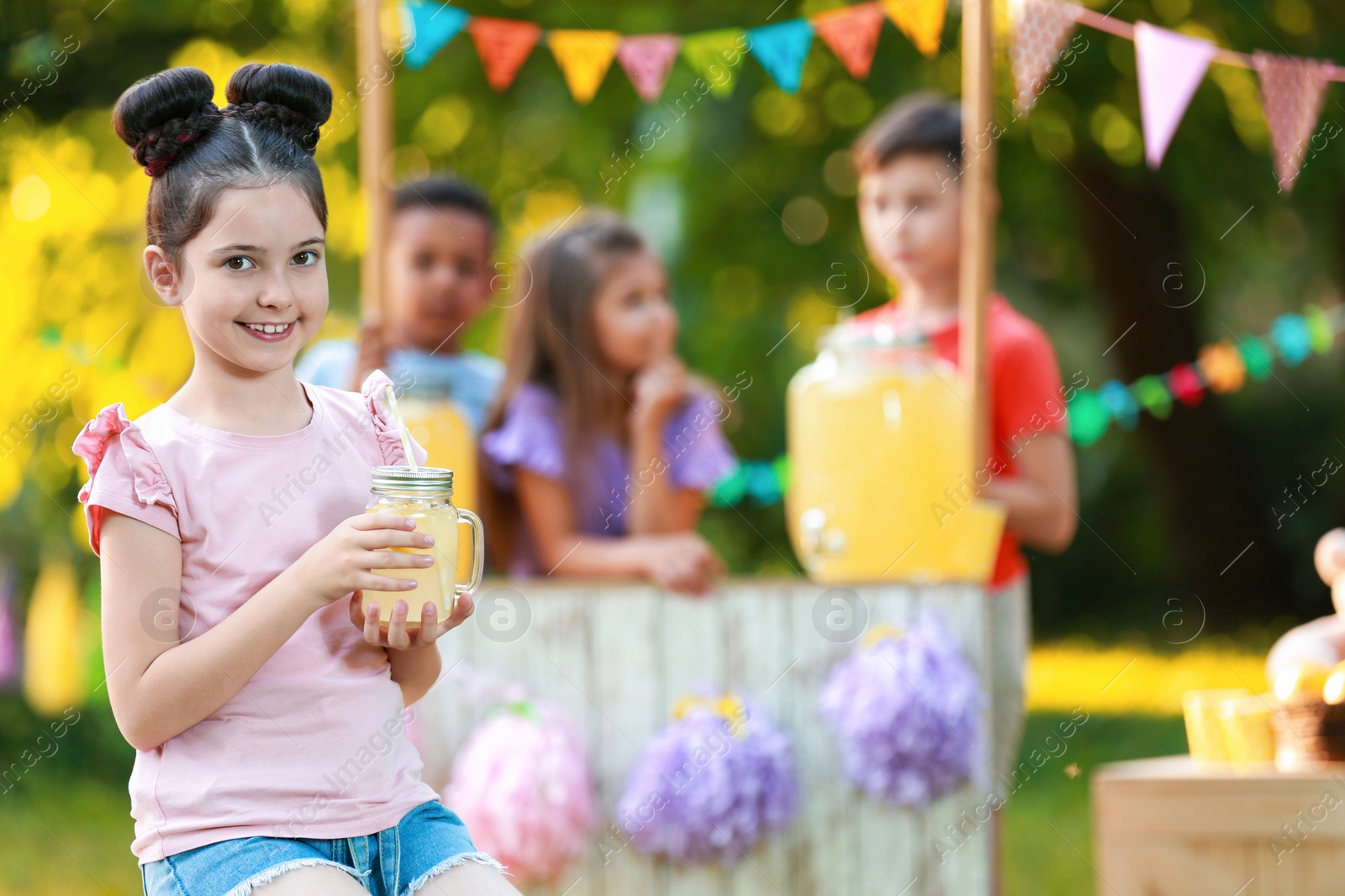 Photo of Cute little girl with natural lemonade in park, space for text. Summer refreshing drink