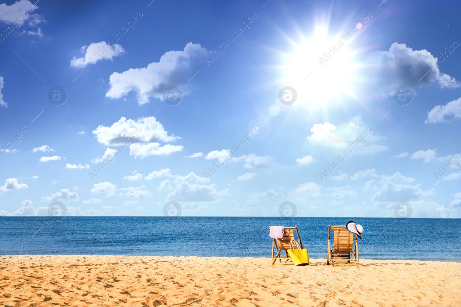 Image of Empty wooden sunbeds on sandy beach near sea on sunny day