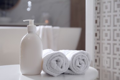 Photo of Bottle of shower gel and fresh towels on white table in bathroom. Space for text